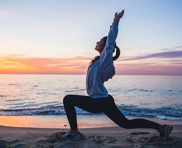 young woman doing sport exercises on sunrise beach in morning, stretching, healthy lifestyle, yoga